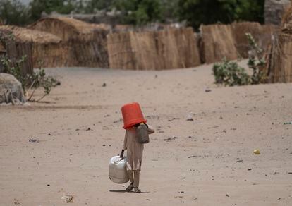 Un niño lleva cubos de agua y garrafas a un pozo para llenarlos en el campamento que acoge a  refugiados huidos de la violencia de Boko Haram.