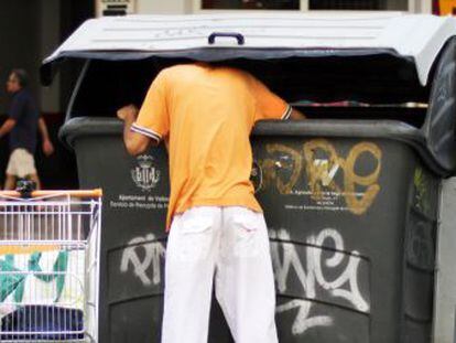 Un hombre rebusca en la basura, ayer, en las calles de Valencia.