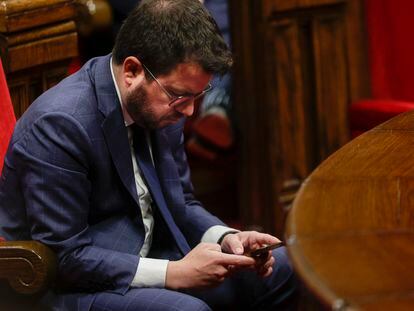 El president de la Generalitat, Pere Aragonés, consulta su teléfono móvil durante una sesión del pleno del Parlament.