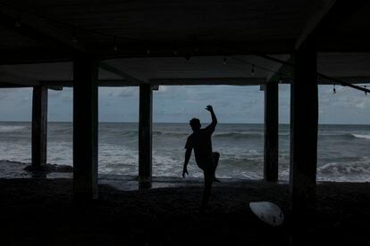 A surfer on the beach of Puerto de La Libertad.  This place has become an attraction for tourists through the use of cryptocurrency. 