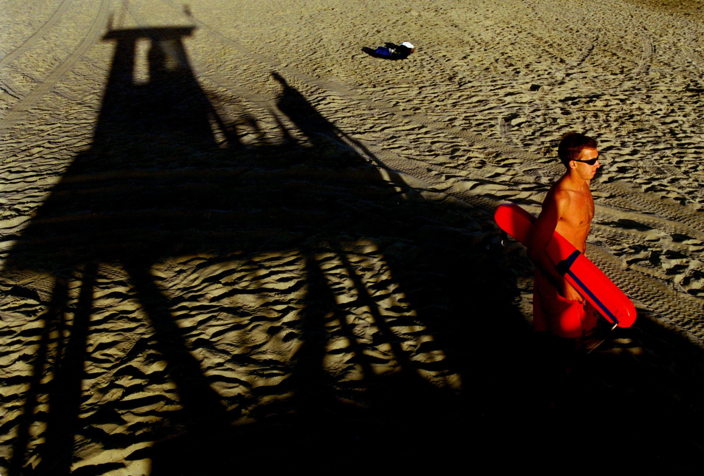 Un vigilante recorre la playa de Newport Beach, California.