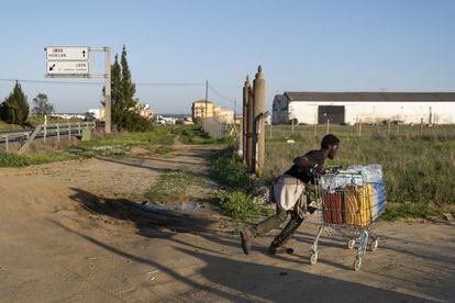 Mohamed, un joven de Gambia que pidió asilo en Italia y ahora trabaja en el campo de Lepe, empuja el carrito con el que consigue llevar agua al asentamiento. La fuente más cercana está en una rotonda a dos kilómetros de distancia.