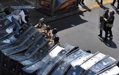 Un manifestante salta sobre los escudos de la polic&iacute;a venezolana.