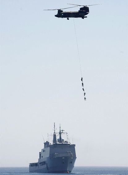 Un helicóptero Chinook, en una maniobra de evacuación, sobrevuela el buque anfibio Galicia durante el simulacro de rescate aeronaval de rehenes que han realizado los tres ejércitos en la playa del Sardinero, en Santander, con motivo del Día de las Fuerzas Armadas.
