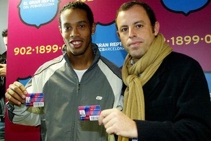 Ronaldinho y Sandro Rosell, en 2004 con los carnets de socios del Barcelona.