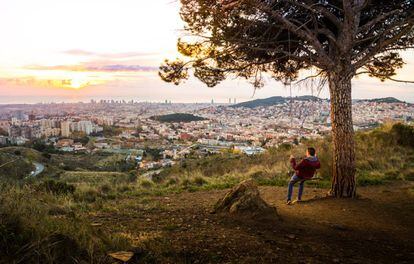 Un joven contempla el atardecer sobre Barcelona desde un columpio colgado de un árbol en las montañas de Collserola.