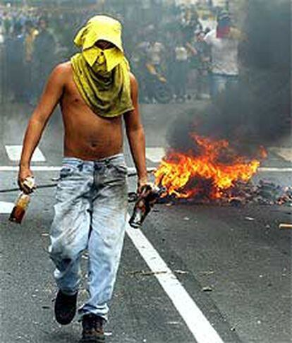Un opositor porta <i>cócteles molotov</i> durante los disturbios de ayer en Caracas.