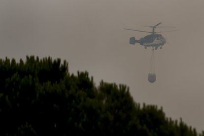 Un helicóptero entre humo sobrevuela la zona del incendio se inició ayer sábado en Doñana entre las localidades de Mazagón y Moguer.