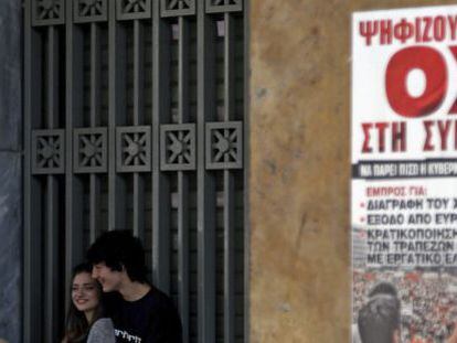 Una pareja junto a un cartel que pide el &quot;no&quot; en el refer&eacute;ndum del domingo, en Atenas