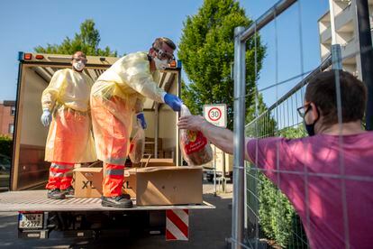 Miembros de Cruz Roja llevan pan a los residentes en cuarentena por el brote en una empresa cárnica en Alemania.