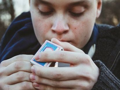 Un adolescente se enciende un cigarro.