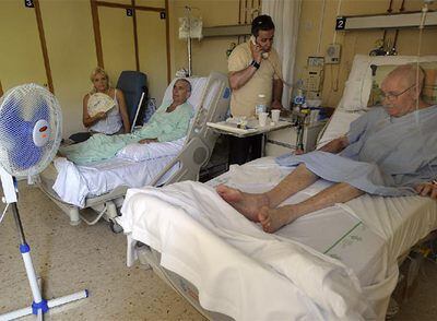 Marcela Jara se abanica junto a su esposo, José Navalón, mientras que otro paciente intenta refrescarse con un ventilador.