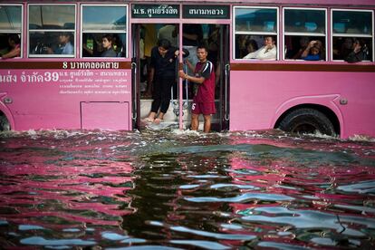 Un grupo de viajeros se asoma a las calles de Bangkok, anegadas por el agua, tras la fuertes lluvias que asolaron Tailandia.