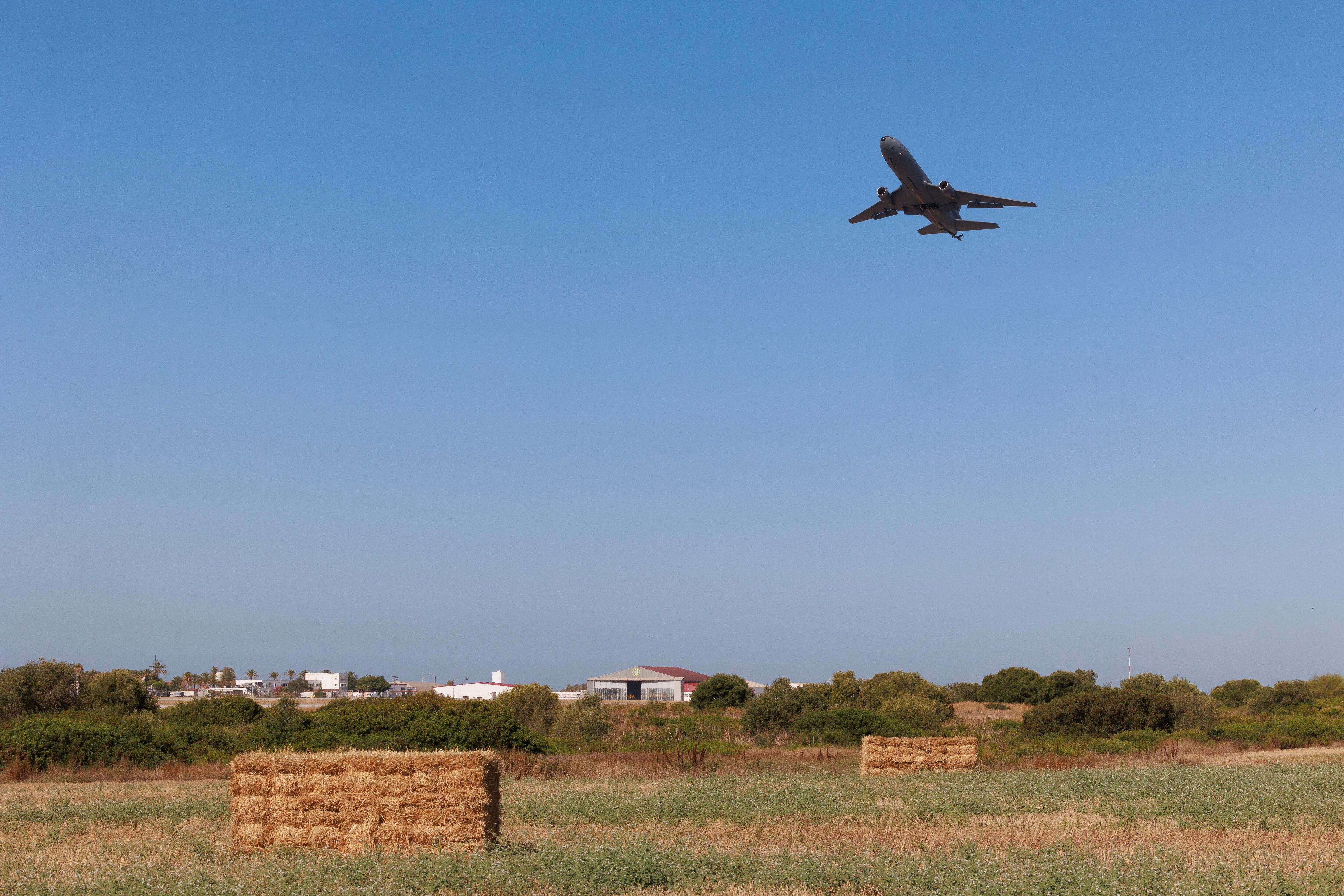 Uno de los aviones despega en la base de Rota bajo el campo de trigo ya recogido.
