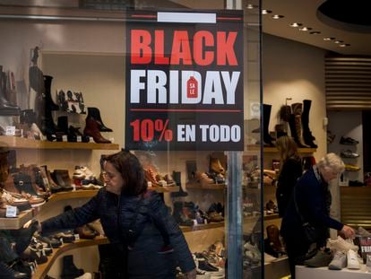 Varias personas compran en una tienda que muestra carteles de rebajas del Black Friday, en Sevilla.