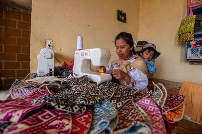 An Otomi woman works making textiles while caring for a child, in Amealco (Querétaro State), in 2020.