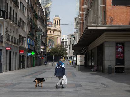 Un hombre pasea a su perro por la céntrica calle de Preciados durante el estado de alarma.