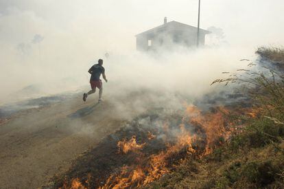 Un vecino escapa del fuego. El incendio ha obligado a desalojar numerosas viviendas, un centro escolar de infantil