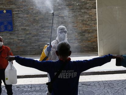 Un trabajador sanitario desinfecta a un ciudadano antes de entrar al ayuntamiento en Manila (Filipinas). En vídeo, las declaraciones de Duterte,.