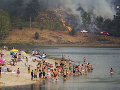Bañistas en Ponte Sampaio contemplan desde la playa el fuego que arrasa el monte.