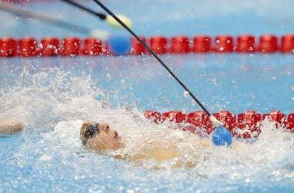 El entrenador utiliza un palo con una punta suave para que Yang Bozun de China sepa que está llegando al final de la piscina durante los 100m Espalda.