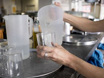 Una mujer echa agua en un vaso en un bar de Sevilla.