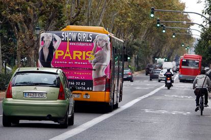 Un autobús metropolitano con publicidad de contactos circula por una calle de Valencia.
