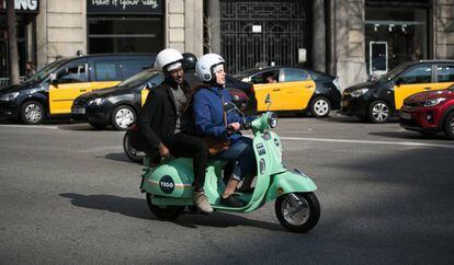 Usuarios de motos de alquiler por minutos de la empresa YeGo circula por la Via Laietana de Barcelona.