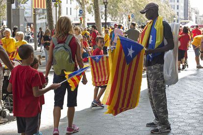 Una familia pasea por el centro de Barcelona junto a un hombre vendiendo 'estelades'.