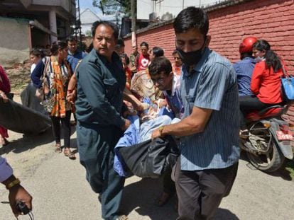 Varias personas socorren a un herido en Katmandú tras el terremoto.