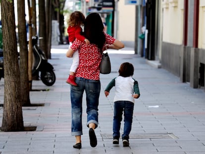 Dos niños acompañados de un adulto por el centro de Madrid durante la pandemia de coronavirus.