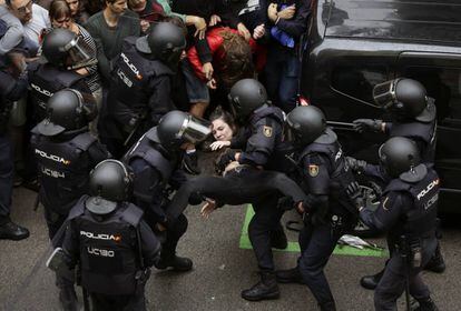 Agentes antidisturbios de la Policía Nacional que han formado un cordón de seguridad trasladan a una joven frente al colegio Ramón Llull de Barcelona.