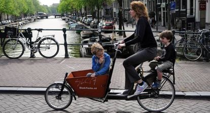 Una madre con sus hijos cruzando en bici uno de los canales de Ámsterdam.