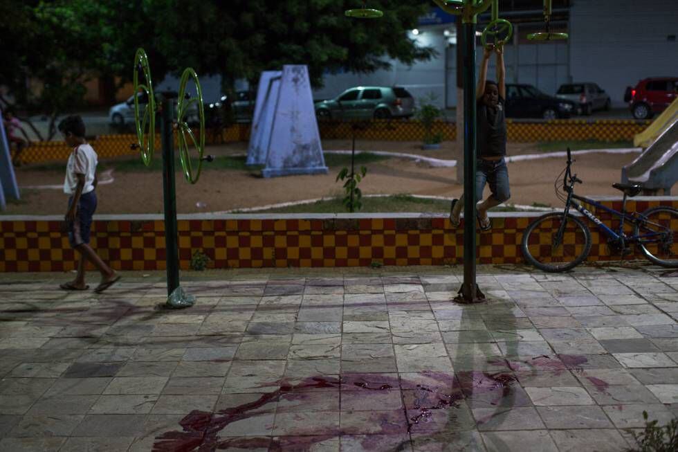 Niños juguetean delante de marca de sangre donde poco antes ocurrió un homicidio, en Natal.