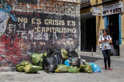 Una joven camina junto a un montón de bolsas de basura en el madrileño barrio de Lavapiés, este lunes.