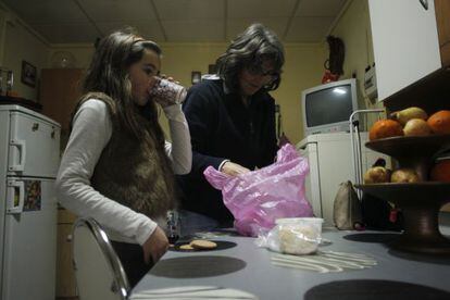 La niña portuguesa Matilde Alexandra Alves bebe un vaso de leche mientras su madre Maria Alexandra Gomez saca de la bolsa la comida dada por el ayuntamiento de Elvas (Portugal).