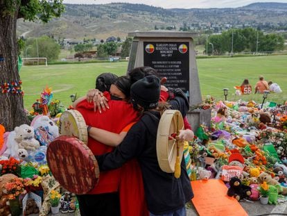 Algunas personas se abrazan frente a un memorial en honor a los niños del internado de Kamloops.