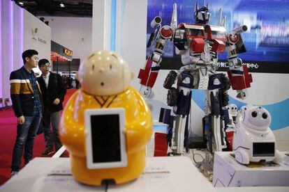 Varias personas observan un robot imitación de Transformers expuesto.