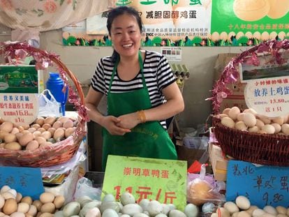 Vendedora de huevos sonríe risueña en su puesto del mercado.