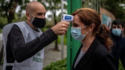 Un voluntario de Más Madrid toma la temperatura a Mónica García a la entrada de un acto celebrado en Leganés, el 24 de abril.

