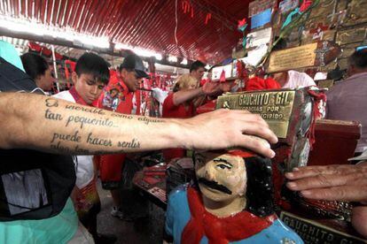 Un hombre apoya su mano sobre una imagen del Gauchito Gil en el santuario de Corrientes.