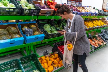 Una mujer compra verduras en un supermercado.