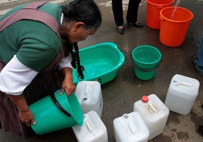 Una mujer coge agua potable de un camión en Irpavi, La Paz, tras un corte del suministro en su distrito.