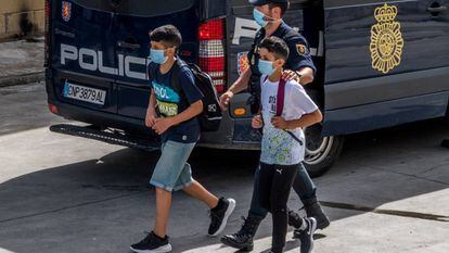 Un policía nacional acompaña a dos menores, el pasado 20 de mayo en Ceuta.