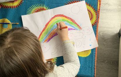 Una niña dibuja un arcoíris.