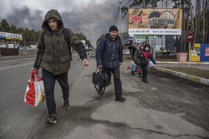 Varios vecinos de Bucha, cerca de Kiev, abandonan la ciudad, el viernes. España va a contar con tres grandes centros de acogida y atención a personas que huyen de la guerra en Ucrania, uno de los cuales estará en Alicante, donde residen 21.000 personas originarias de ese país.
