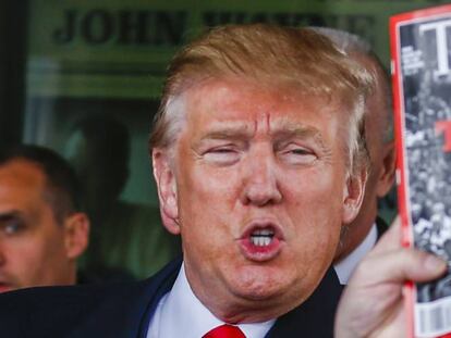 Donald Trump sostiene un ejemplar de la revista Time.