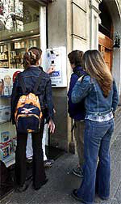 Varios jóvenes compran preservativos en una máquina instalada en el exterior de una farmacia de Barcelona.