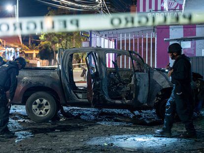 Policías inspeccionan un auto que explotó afuera de una oficina gubernamental en Quito (Ecuador), en agosto.