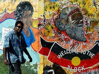 Un aborigen australiano pasa por delante de un mural de arte indígena en Redfern, un barrio periférico de Sidney.